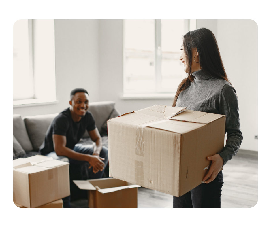 A young couple looking at each other while the girl is holding a moving box